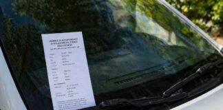 parabrezza di un auto con una multa poggiata sopra