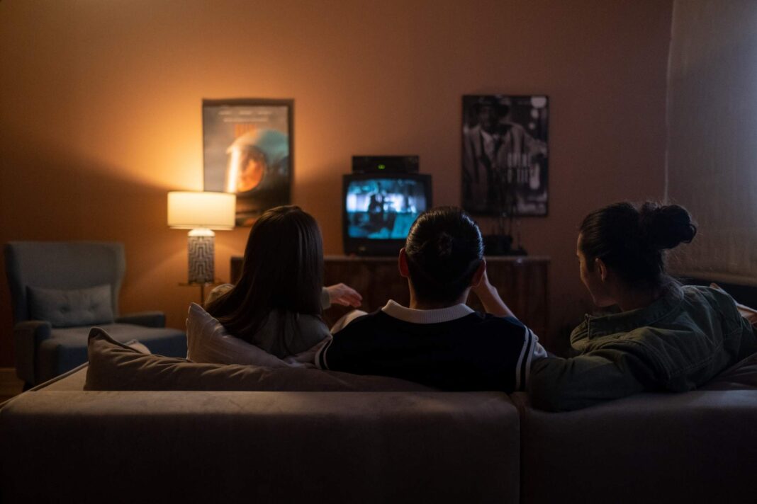 3 persone guardano la tv sedute sul divano