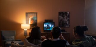 3 persone guardano la tv sedute sul divano